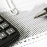 Close-up of a calculator and pen on a bar graph, representing finance and accounting.